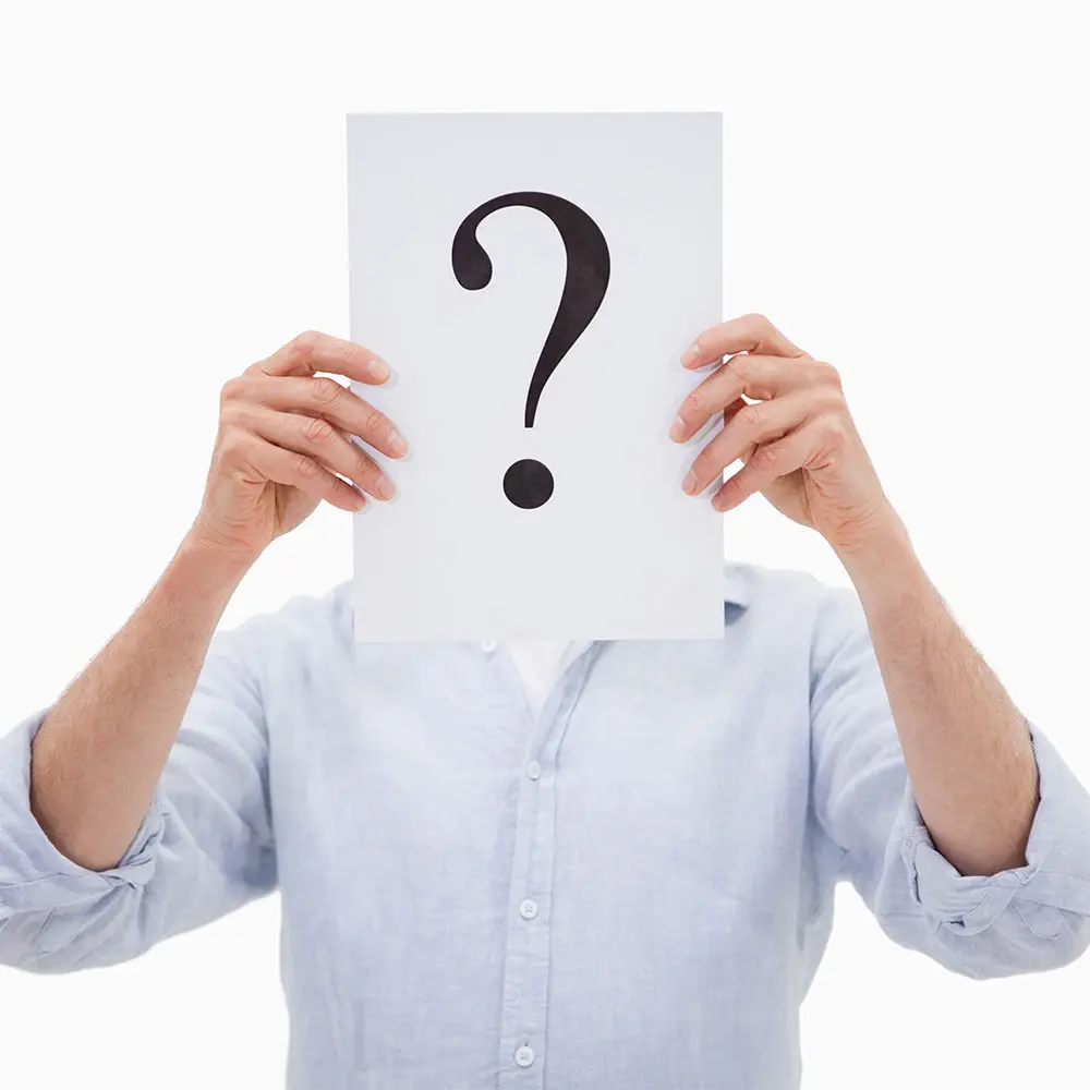An image of an anonymous person in a white shirt holding up a piece of paper with a large black question mark on it.