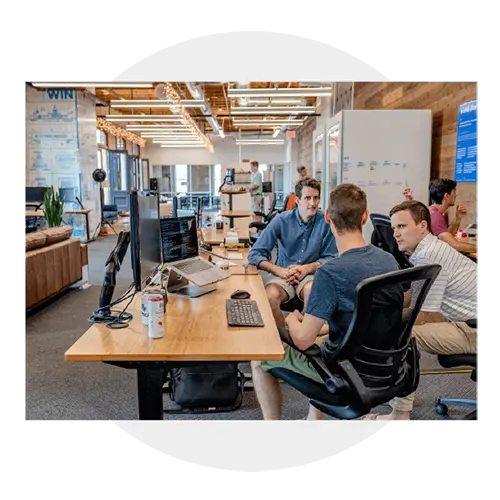 An image of three men sitting around a computer having a conversation about something.